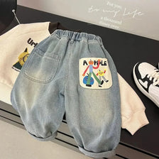 Light blue denim casual pants with an embroidered graphic featuring a smiling apple and people