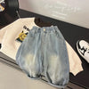 Light wash denim jeans and a cream sweatshirt laid out on a dark surface.