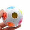 A white rainbow fidget cube with colorful inserts is held in a hand.