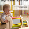 A wooden spinning drum toy for toddlers is shown on a table, demonstrating rotation to stimulate senses.