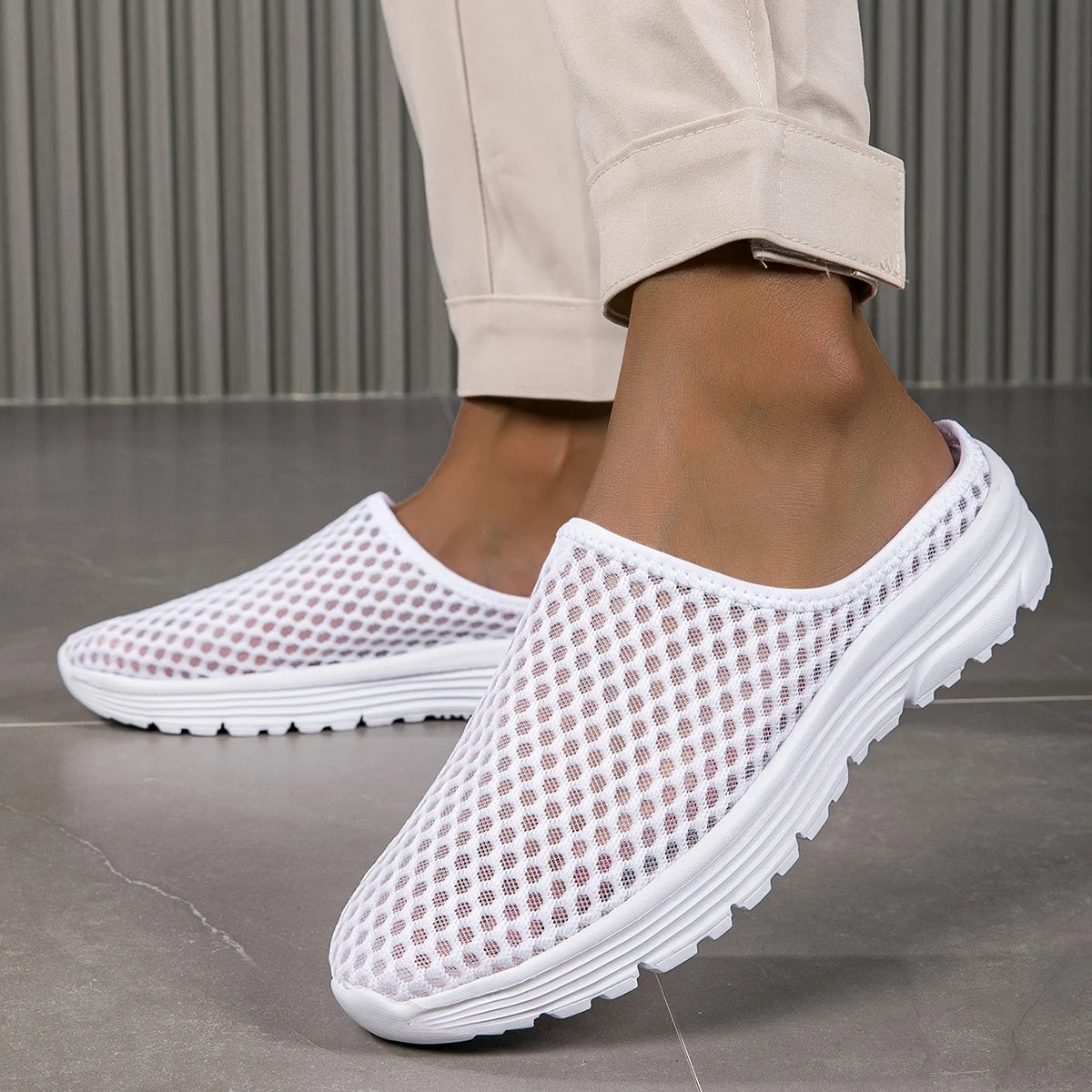 White breathable slide sandals with a perforated design shown on a person's foot.