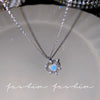Silver heart pendant necklace featuring a blue iridescent crystal surrounded by small clear stones and angel wings.