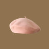 A soft pink classic wool beret hat for women shown against a brown background.