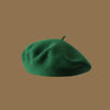 A close-up view of a deep green wool beret hat.