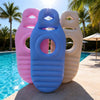 Three inflatable maternity support pillows in pink, blue, and cream stacked outdoors by a pool.