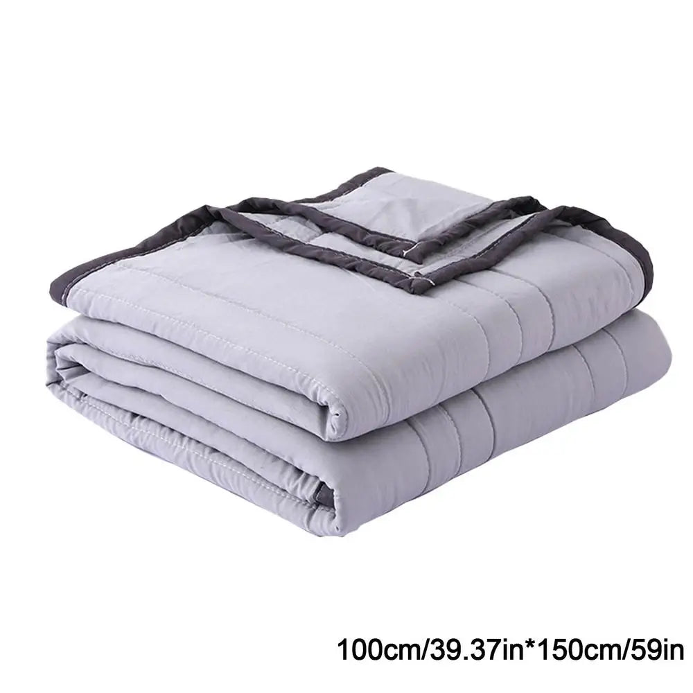 A stack of light gray breathable cooling throw blankets folded and rolled.