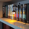 Eine Bücherregallampe mit Vintage-Geisterbüchern und warmem LED-Licht auf einem weißen Regal.