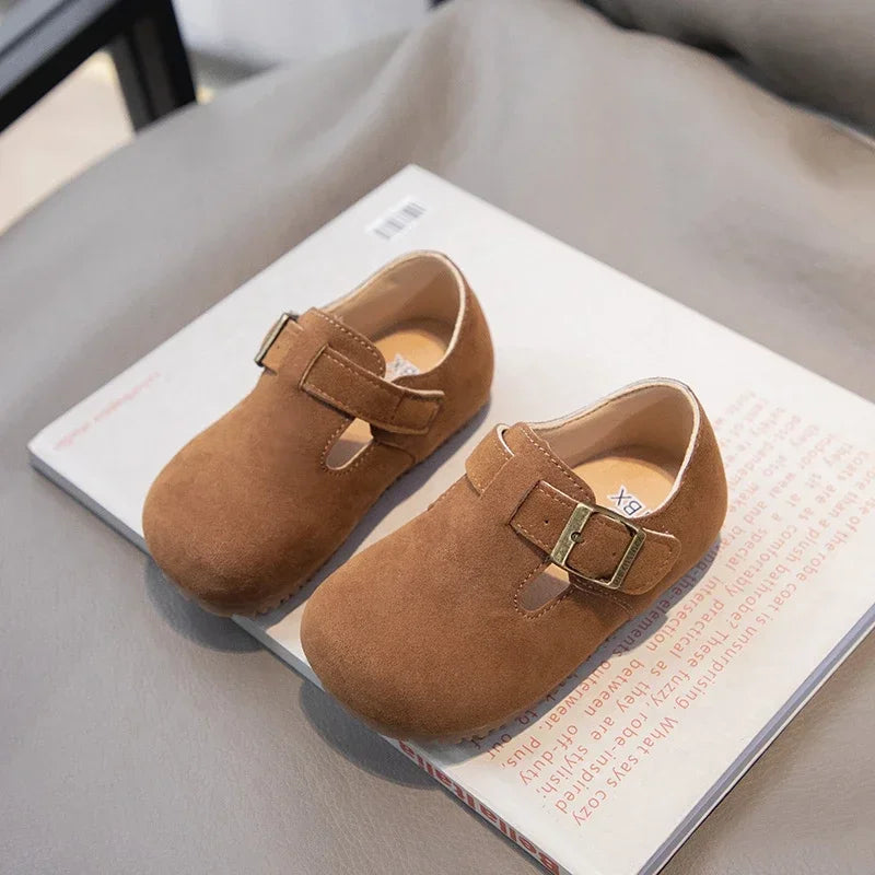 A pair of tan retro non-slip kids' moccasin shoes with a hook-and-loop closure resting on a white box.