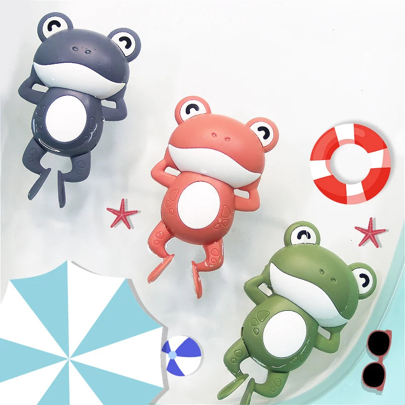 Three wind-up frog bath toys in gray, pink, and green are shown against a white background.