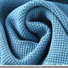 A close-up of light blue knitted beach shorts rolled into a spiral.