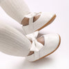A pair of white soft non-slip baby first walker shoes worn on a person's foot.