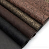 Rolls of vintage floral textured faux leather fabric in various brown and black tones