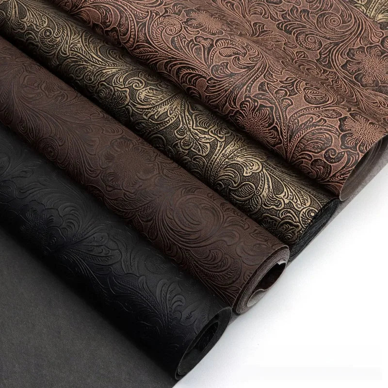 Rolls of vintage floral textured faux leather fabric in various brown and black tones