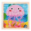 A wooden jigsaw puzzle featuring a pink, smiling, jellyfish-like creature against a blue and green background.