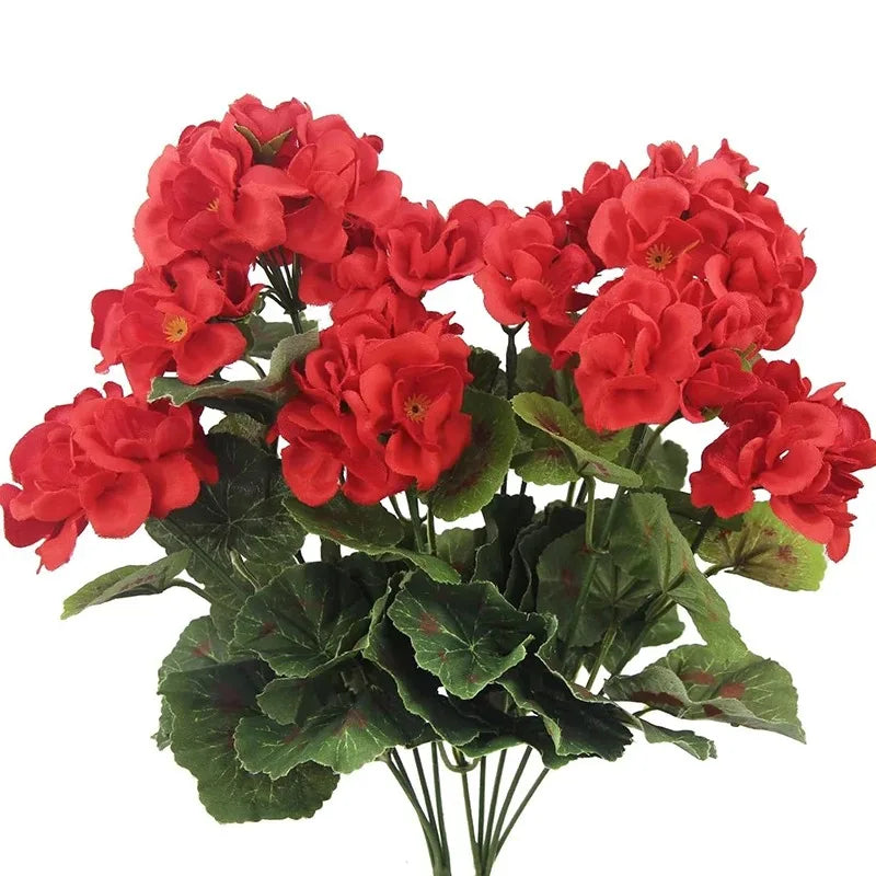 A bouquet of lifelike red artificial geranium flowers with green leaves.