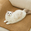A fluffy white cat is lying on a brown sisal scratching mat.