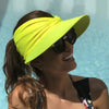 A woman wearing a bright yellow UV-protective beach hat and sunglasses outdoors.