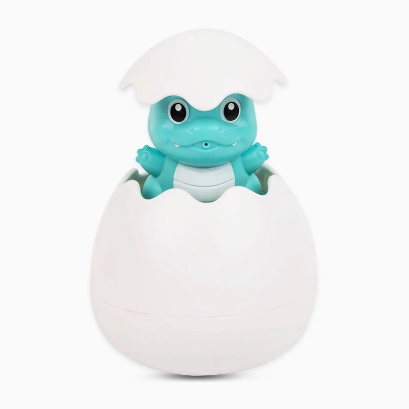 A cute, light blue frog-like toy with large eyes is emerging from a white egg-shaped container.