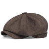 A dark brown vintage newsboy cap with a folded brim shown from the top.