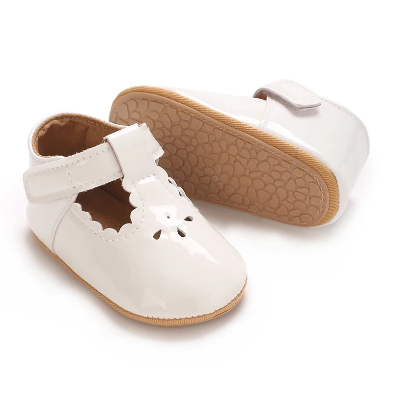 A pair of white soft non-slip baby first walker shoes with a textured tan sole.