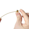 A hand holds a thin, golden bamboo skewer with a pearl-like tip.