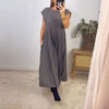 A woman wearing a sleeveless pleated midi dress in gray standing indoors.