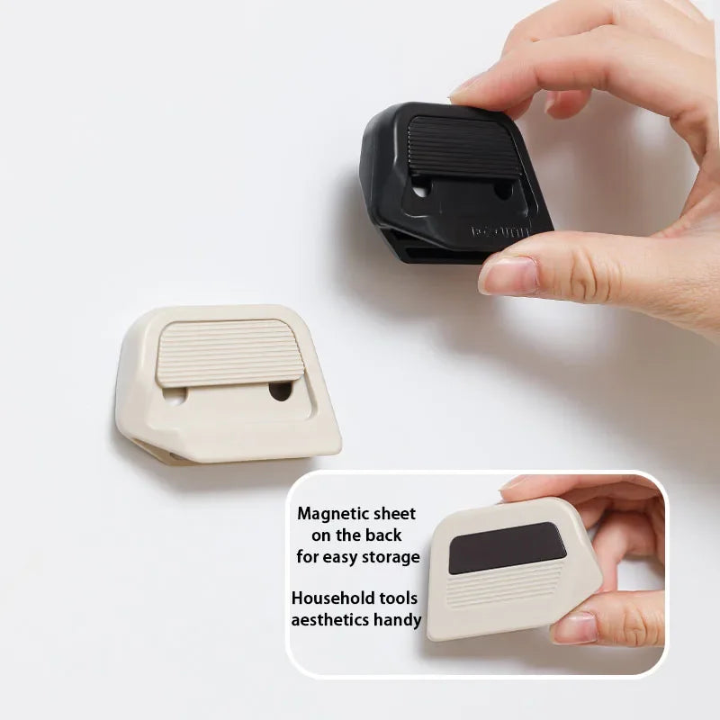 A hand is holding a black magnetic sheet storage component and a light beige version of a retractable ceramic blade cutter.