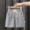 Gray kids beach shorts with an elastic waist and a hanging wooden hanger