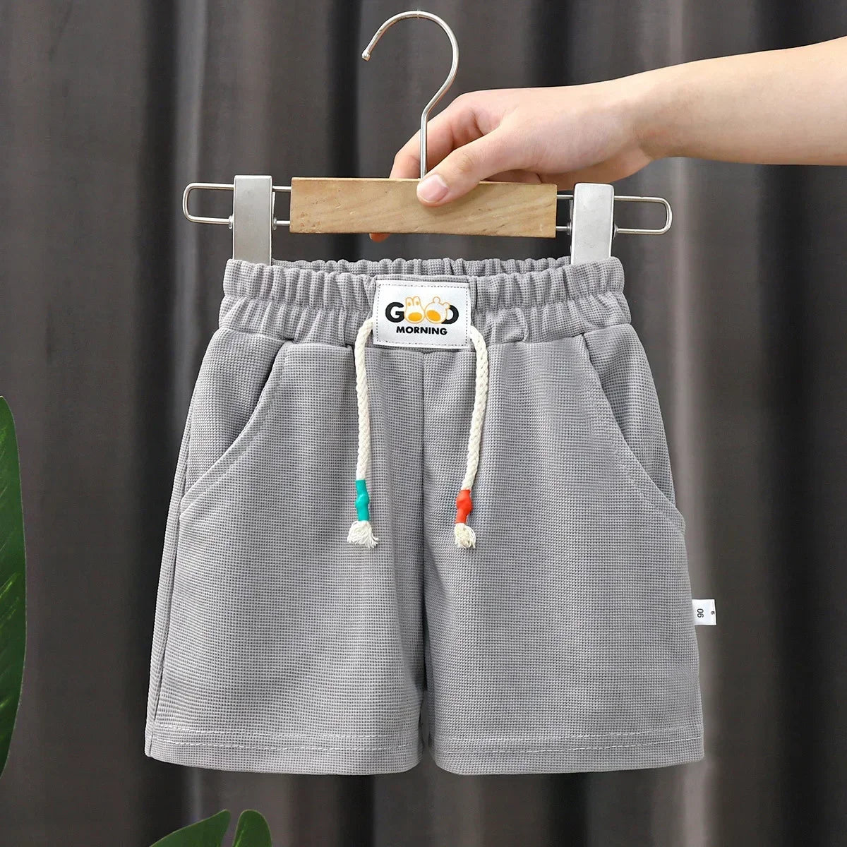Gray kids beach shorts with an elastic waist and a hanging wooden hanger
