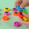 A hand is holding and manipulating colorful plastic fidget spinner building blocks.