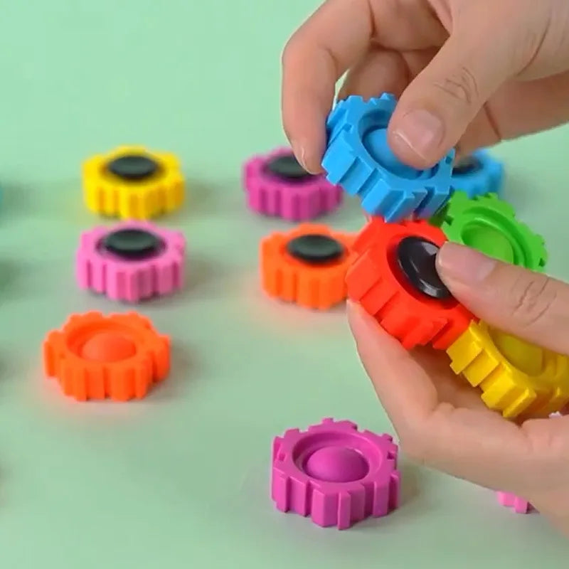 A hand is holding and manipulating colorful plastic fidget spinner building blocks.