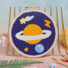 Kit de bordado punch needle morado y amarillo con diseño celestial en lienzo circular.