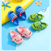 A collection of colorful kids shark clog sandals in blue, pink, and green are displayed on a light blue background.