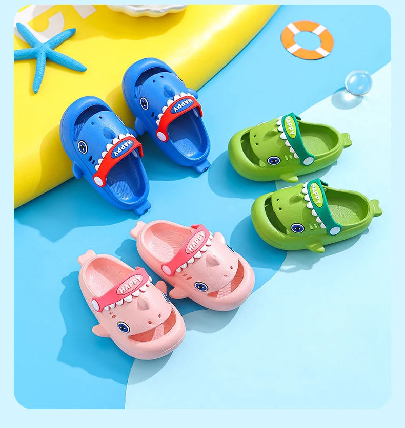 A collection of colorful kids shark clog sandals in blue, pink, and green are displayed on a light blue background.