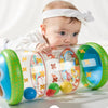 A baby is interacting with a clear plastic roller toy filled with colorful balls for tummy time and sensory development.