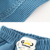 Close-up of blue kids beach shorts with an elastic waist featuring a woven trim and a tag.