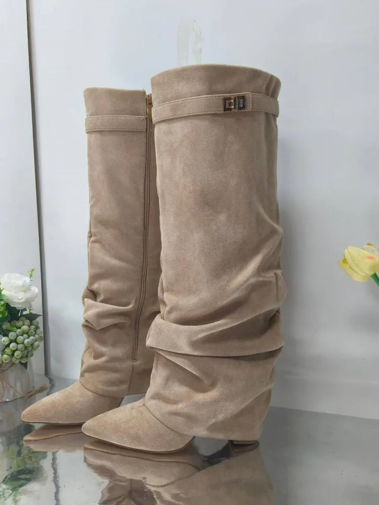 A pair of beige knee-high chunky heel boots with a metal buckle standing upright.