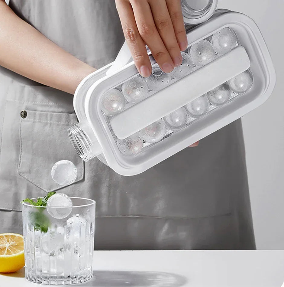 En hånd holder et hvitt silikonbrett fylt med iskuler, ved siden av et glass vann og en sitron.