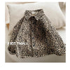 A close-up of a boy's leopard print denim shirt folded on a light-colored cushion.