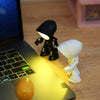 A cartoon hero police night light figure is placed on a laptop keyboard next to a yellow spherical object.