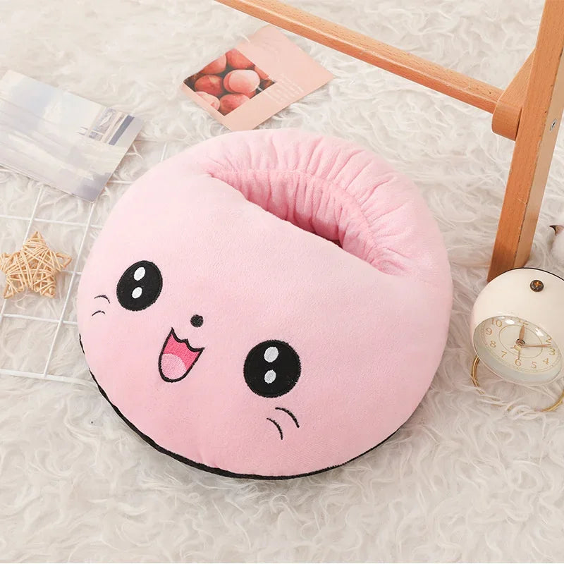 A pink plush foot warmer with a cute face design resting on a white fuzzy surface.