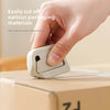 A hand is using a white retractable ceramic blade cutter with a magnetic lock to easily cut packaging materials.