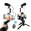 Una mano sostiene un kit de vlogging para teléfono con cámara, trípode, luz LED y micrófono.