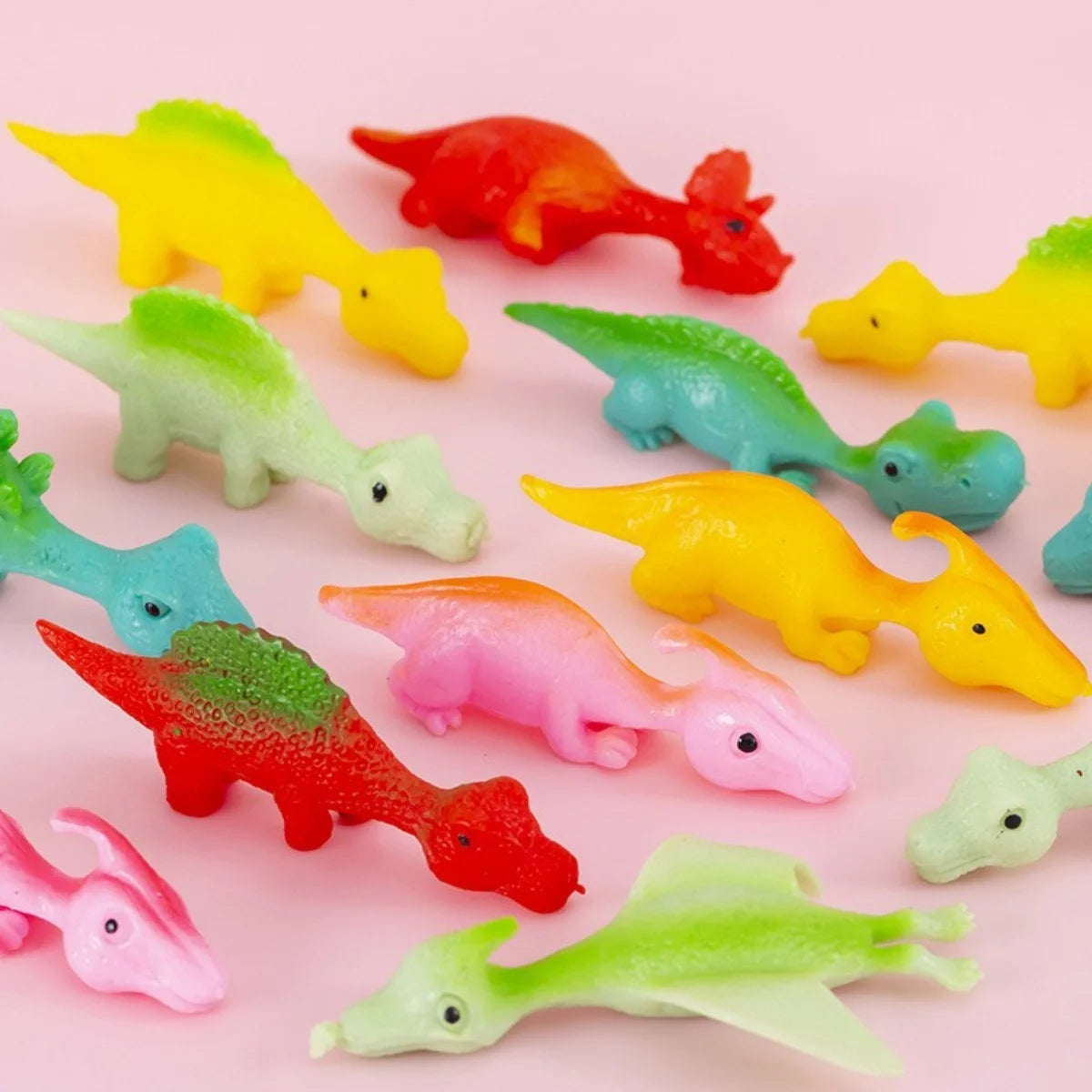 A collection of colorful dinosaur finger catapult toys in various bright colors like yellow, red, green, and pink.