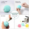 A fluffy teal plush toy ball is shown being handled and used to remove an insulation film, with other colored plush toys near