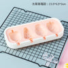A white silicone mold tray containing four pink popsicle shapes on a black wire rack.