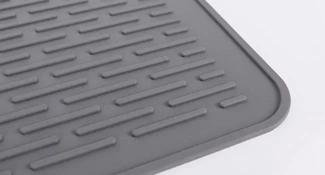 A gray silicone stove protector mat with raised ridges for use on induction and glass-top cooktops.