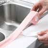 En hand applicerar rosa självhäftande PVC-tätningstejp på en vit diskho eller bänkskiva.