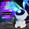 A white astronaut projector casts a green light with galaxy effects onto a dark surface.