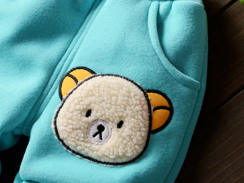 A light turquoise fleece pajama top featuring a cute yellow bear design on the chest.